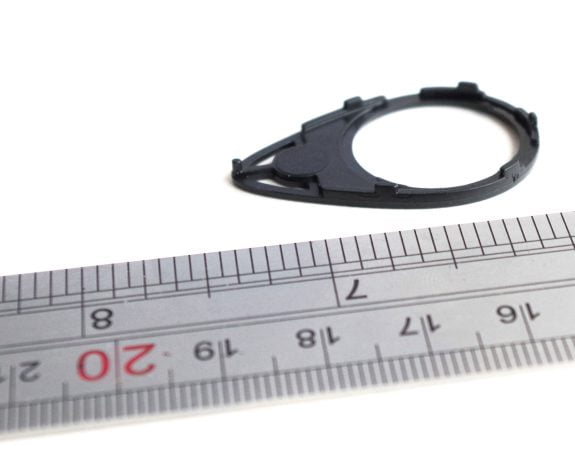 Micro injection moulded plastic component shown alongside a ruler for scale